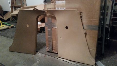 1985 Ford Bronco - Two large, tan-colored car door panels with circular cutouts are leaning against cardboard boxes in a garage setting. A broom and dustpan a…