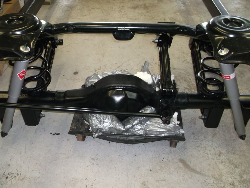 Black rear axle assembly with shocks and springs.