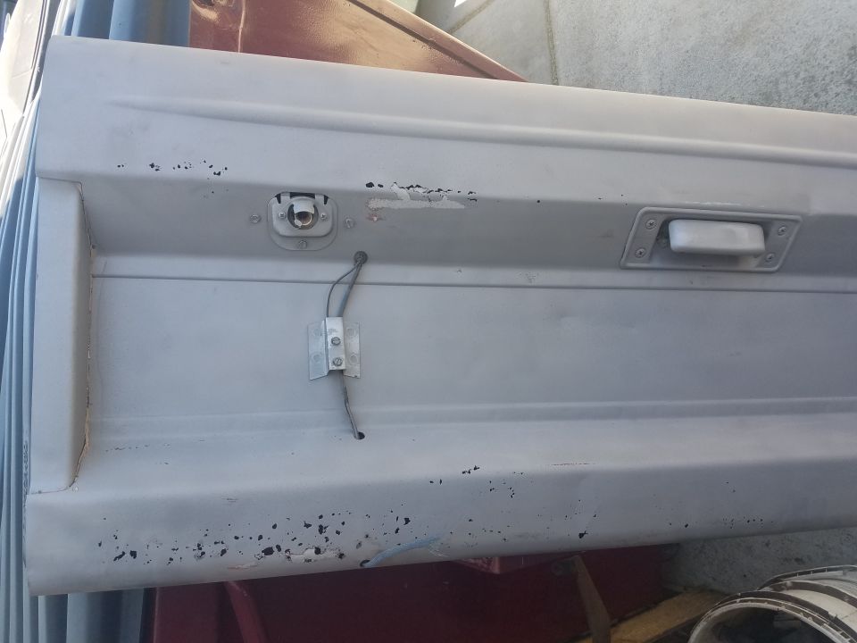 Close-up of a light gray vehicle door with a white handle and electrical wire.
