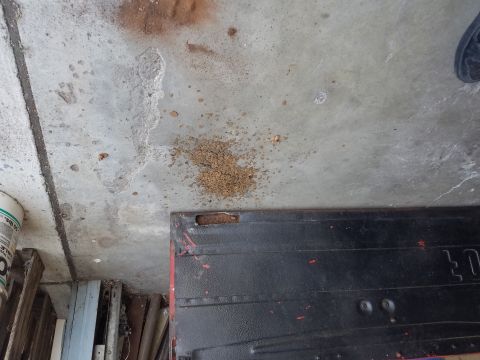 1968 Ford Bronco - This image shows a concrete floor with some debris and a black metal object with red accents. There are also some wooden planks and a white…