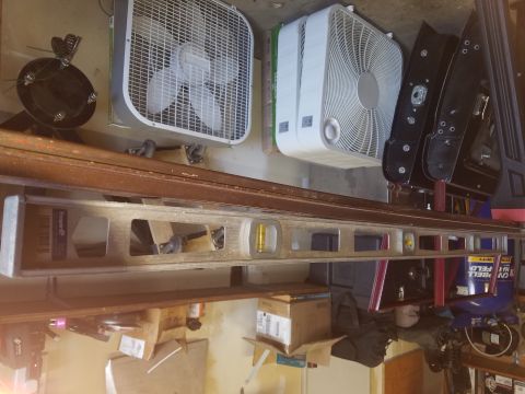 1968 Ford Bronco - A collection of items including two box fans, a black car door, and a long level are arranged on shelves. The scene is cluttered with vario…