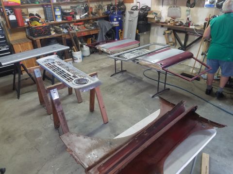 1968 Ford Bronco - Two car doors and a grille are laid out on sawhorses in a workshop. A person in a green shirt stands in the background near a workbench.