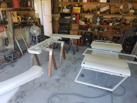 1968 Ford Bronco - Several white vehicle body panels, possibly doors and a grille, are laid out in a garage setting. The panels appear to be prepped for paint…