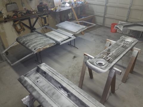 1968 Ford Bronco - Several automotive body panels, including what appears to be a hood and a grille, are laid out in a garage setting, possibly undergoing res…