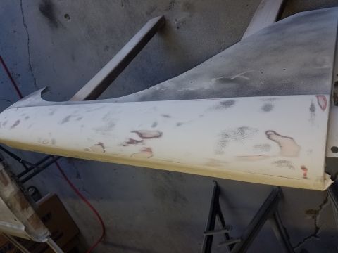 1968 Ford Bronco - A car door, likely from a 1968 Ford Bronco, is shown being prepped for paint. It is resting on sawhorses and has primer and some filler vis…