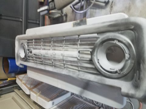 1968 Ford Bronco - A close-up, slightly angled view of a primer-coated front grille assembly for a classic Ford Bronco. The word "FORD" is visible in raised l…