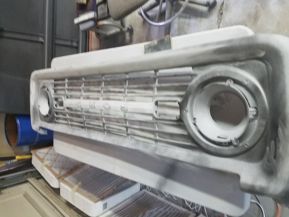 Primer-coated Ford Bronco grille assembly with raised "FORD" lettering.