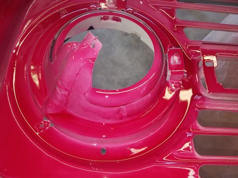 1968 Ford Bronco - A close-up view of a newly painted bright pink metallic headlight bucket and grille area of a classic vehicle. The paint appears to have a…