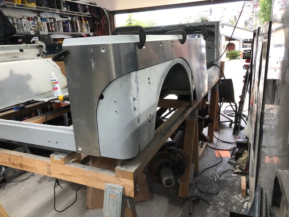 Jeep Wrangler rear body section with new metal fender flare attached, supported by sawhorses.