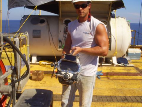 1992 Ford Bronco - A man in a white sleeveless shirt and sunglasses holds a diving helmet while standing on a yellow deck with a submersible in the background.