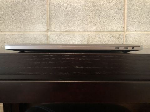 1989 Ford Bronco - The image shows the side profile of a closed silver laptop computer resting on a dark wooden surface. The laptop has two USB-C ports and a…