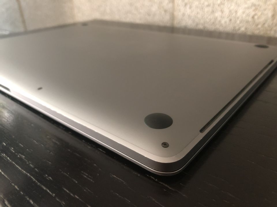 Close-up of a silver laptop bottom with a rubber foot and screw.
