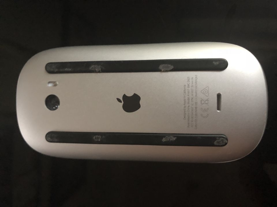 Underside of a silver Apple Magic Mouse with black feet.