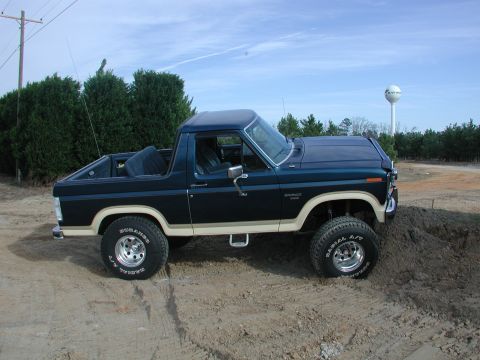 1985 Ford Bronco - This lifted Ford Bronco is shown off-road with a water tower in the background.