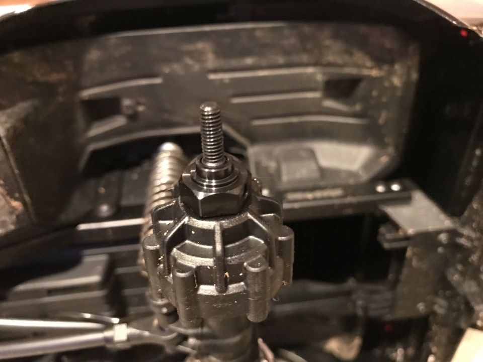 Close-up of a black bolt and plastic component, possibly from a vehicle's drivetrain.
