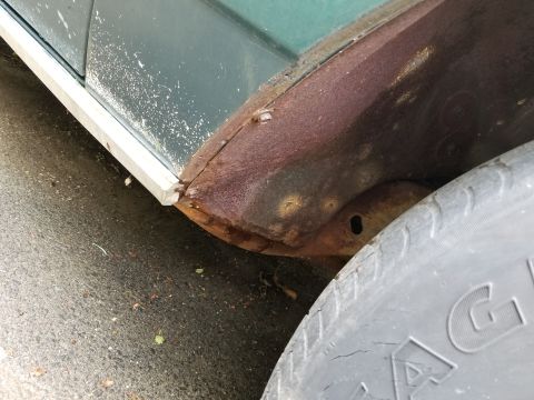 2001 Ford Crown Victoria - Photograph of a rusty lower body panel and tire, not a technical document.