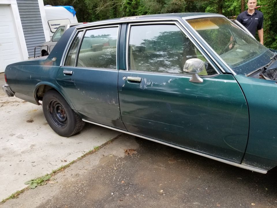 Driver-side profile of a green Chevrolet Caprice sedan in a driveway