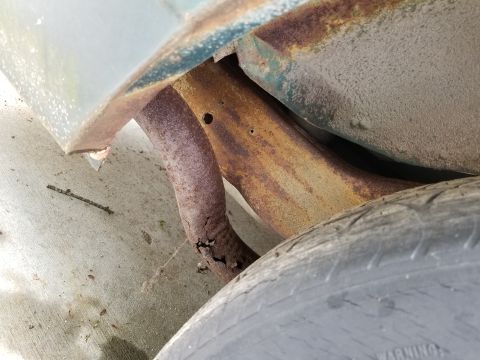 2001 Ford Crown Victoria - The underside of a vehicle shows significant rust on the exhaust system and frame components.