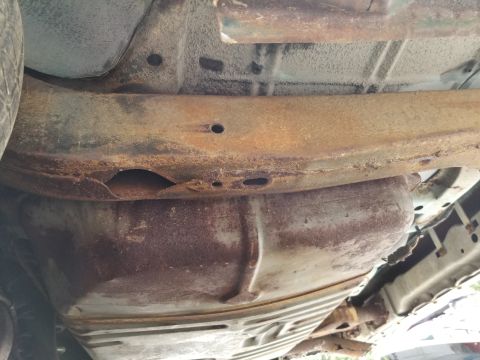 2001 Ford Crown Victoria - The underside of a vehicle reveals a rusty fuel tank and frame, indicating extensive corrosion.