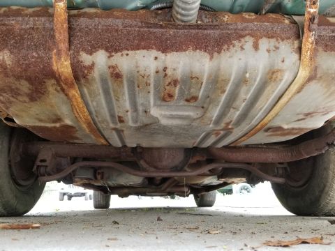 2001 Ford Crown Victoria - The underside of a car reveals significant rust on the fuel tank and exhaust components.