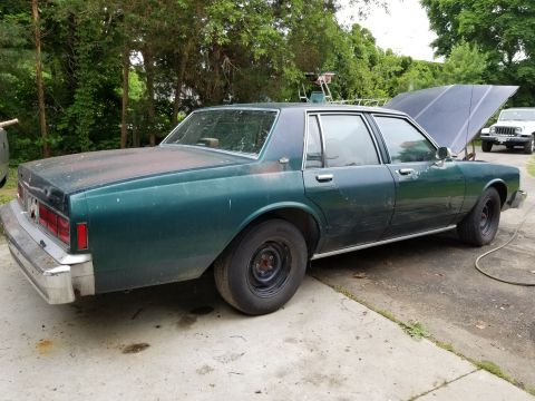 2001 Ford Crown Victoria - Green sedan with hood open, parked next to a white Jeep in a driveway.