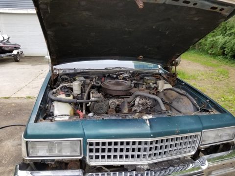 2001 Ford Crown Victoria - The engine bay of a green Chevrolet is exposed with the hood raised, revealing the engine components and front grille.