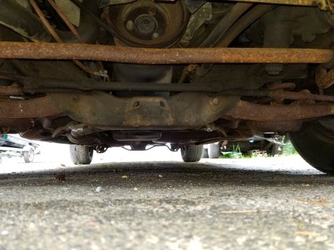 2001 Ford Crown Victoria - The underside of a vehicle shows significant rust on its suspension and exhaust system.