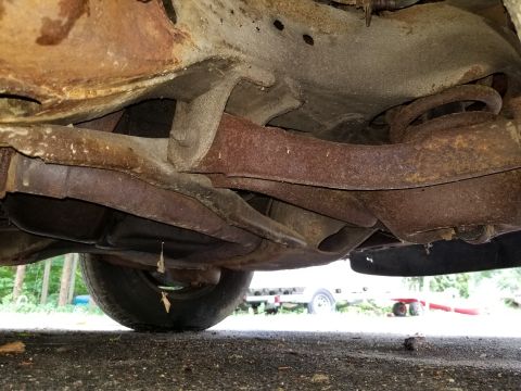 2001 Ford Crown Victoria - The underside of a car shows significant rust on the frame and suspension parts.