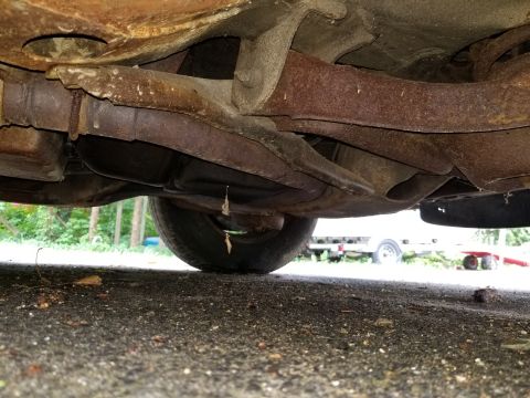 2001 Ford Crown Victoria - The undercarriage of a vehicle displays significant rust on its exhaust system and frame components.
