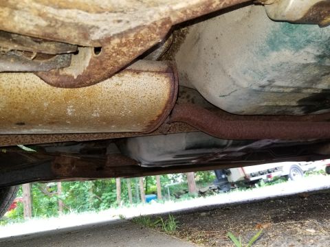 2001 Ford Crown Victoria - The underside of a vehicle is visible, a rusted exhaust system and fuel tank. The registry claims it is a 2001 Ford Crown Victoria, but thi…