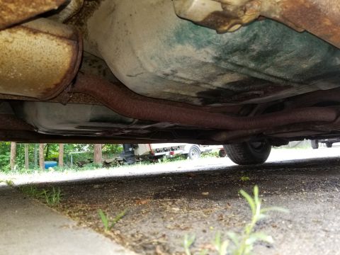 2001 Ford Crown Victoria - Underside of a car, showing exhaust and fuel tank components, with a trailer in the background.