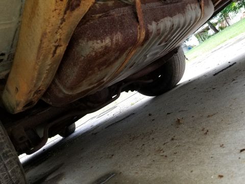 2001 Ford Crown Victoria - The underside of a vehicle displays significant rust on its fuel tank and structural components.