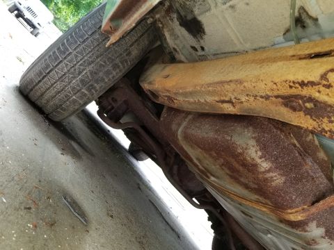 2001 Ford Crown Victoria - The underside of a vehicle displays significant rust and corrosion, with a tire visible.