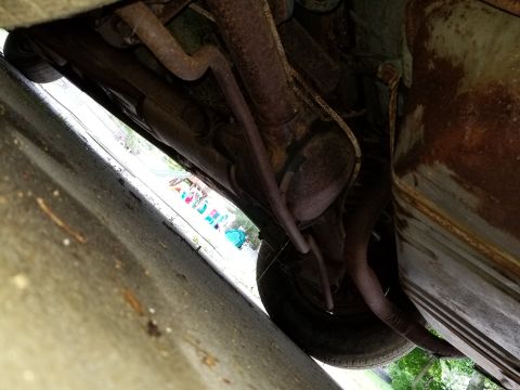 2001 Ford Crown Victoria - The underside of a vehicle is shown, with focus on the rusty exhaust system and a tire. No specific year or model is identifiable from this…