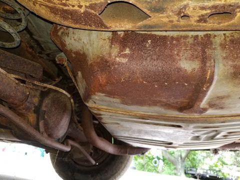 2001 Ford Crown Victoria - The undercarriage of the vehicle displays significant rust on the fuel tank and surrounding components.