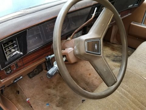 2001 Ford Crown Victoria - The interior of a car shows a tan steering wheel and dashboard with a vent and instrument cluster.
