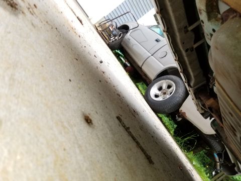 2001 Ford Crown Victoria - A white pickup truck is seen from a low angle, partially obscured by a concrete wall.