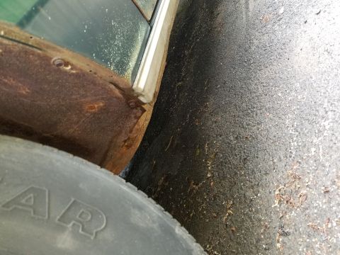 2001 Ford Crown Victoria - Rusted fender and tire detail on a vehicle parked on asphalt.