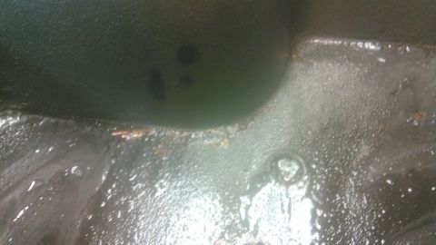 1992 Ford Bronco - The interior floor of a vehicle appears wet and dirty, with debris scattered across it.