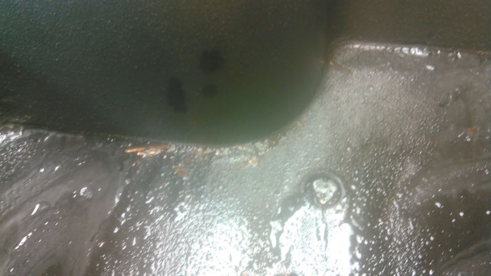 Dark green interior floor with water and debris, showing a circular indentation