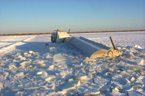 1979 Ford Bronco - A truck is partially submerged in ice and snow, with a large cylindrical object also stuck in the ice nearby.