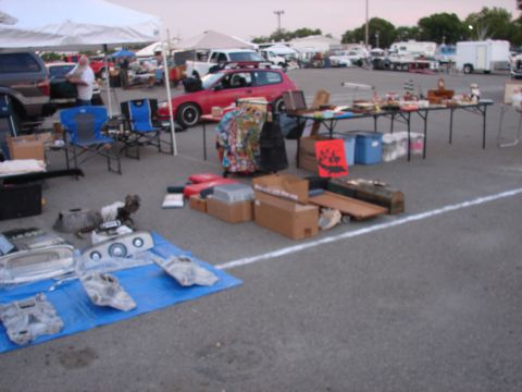 1973 Ford Ranchero - Various car parts are laid out on a blue tarp at an outdoor market.