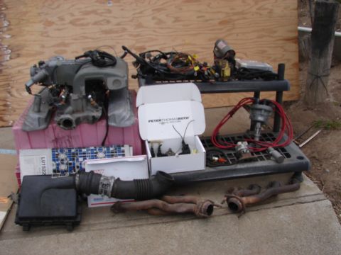 1973 Ford Ranchero - Various engine components are displayed on a shelf and the ground, including an intake manifold and exhaust headers.