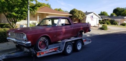 1966 Ford Ranchero - A red 1966 Ford Ranchero is transported on a U-Haul trailer, viewed from the front three-quarter angle.