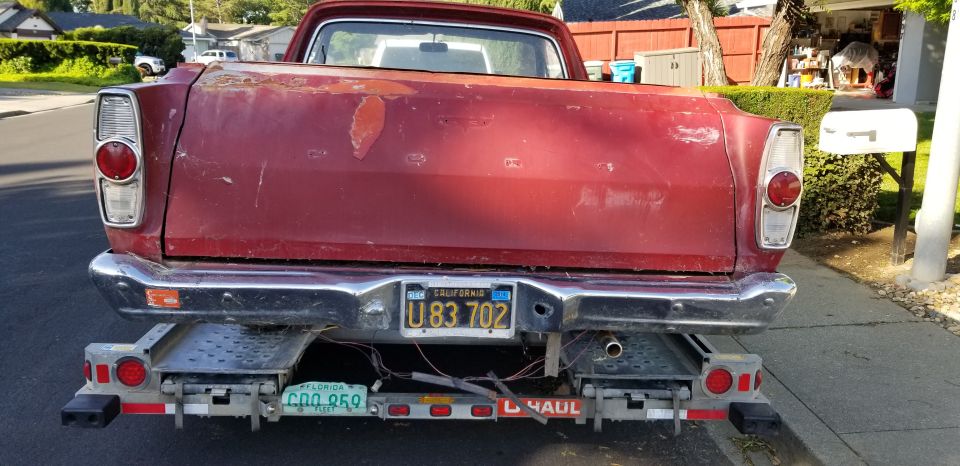Rear view of a red pickup truck bed on a trailer. California plate U83 702