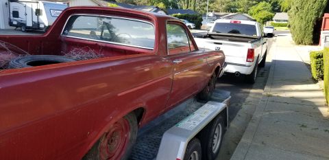 1966 Ford Ranchero - A red 1966 Ford Ranchero is being towed on a trailer, with a white pickup truck behind it.