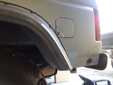1985 Ford Bronco - Close-up of a truck's rear side panel, a fuel filler door and signs of rust.