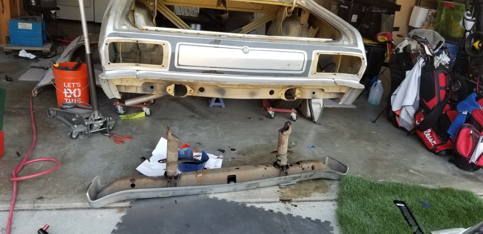 car body being worked on, bumper removed, jack and tools nearby