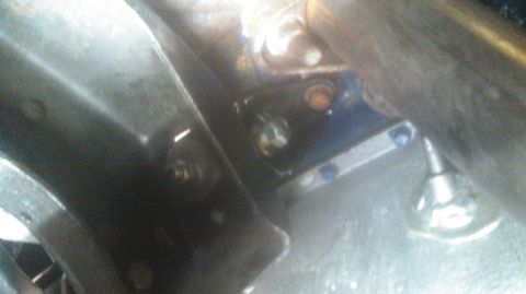 1992 Ford Bronco - A close-up view of engine bay components, including bolts and metal brackets, with some parts painted blue.