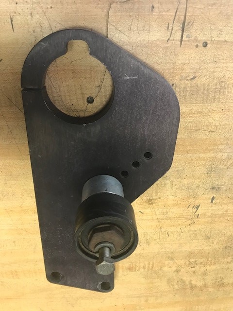 2000 Ford Explorer - A close-up view of a metal bracket with a roller, likely an engine component, against a wooden background.